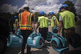 SEVERAL SERVICEMASTER TECHNICIANS MOVE EQUIPMENT INTO A COMMERCIAL BUILDING TO BEGIN THE RESTORATION PROCESS